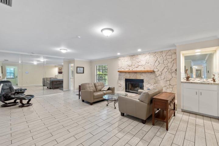 Huge 16'x23' living room with a wood burning fireplace, wet bar, porcelain plank flooring, and crown molding.