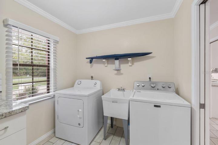 Spacious laundry room featuring a laundry sink, and added cabinets with counter space, and  direct access to the garage.