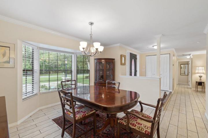 Spacious formal dining room featuring porcelain plank tile, crown molding, and a large bay window.