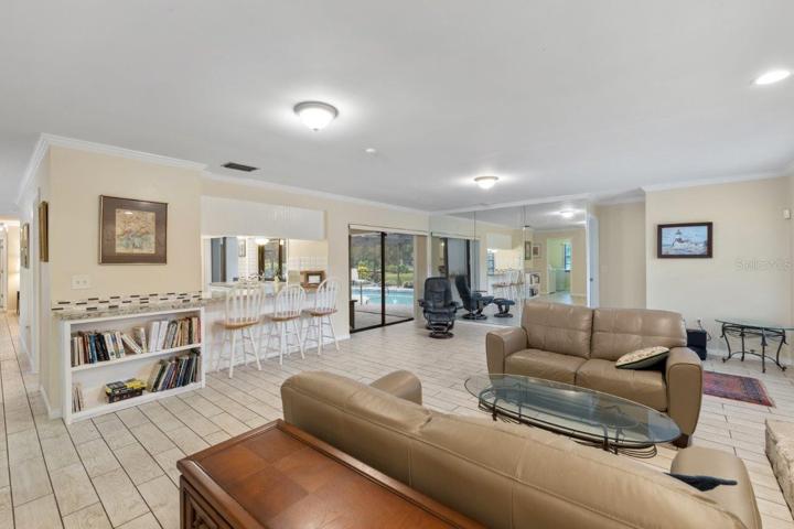 Huge 16'x23' living room with a wood burning fireplace, wet bar, porcelain plank flooring, and crown molding.