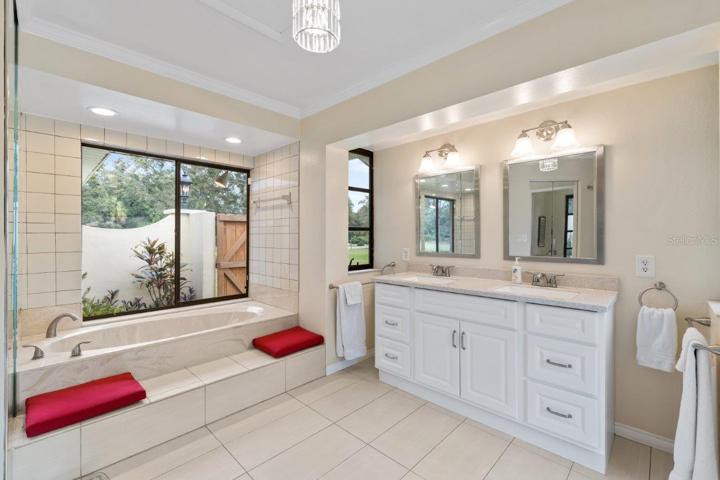 Owners ensuite bathroom featuring dual sinks, garden tub and walk-in showers with courtyard windows, and walk-in closet.