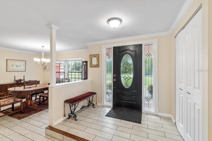 Front foyer featuring crown molding, porcelain plank tile, and coat closet.