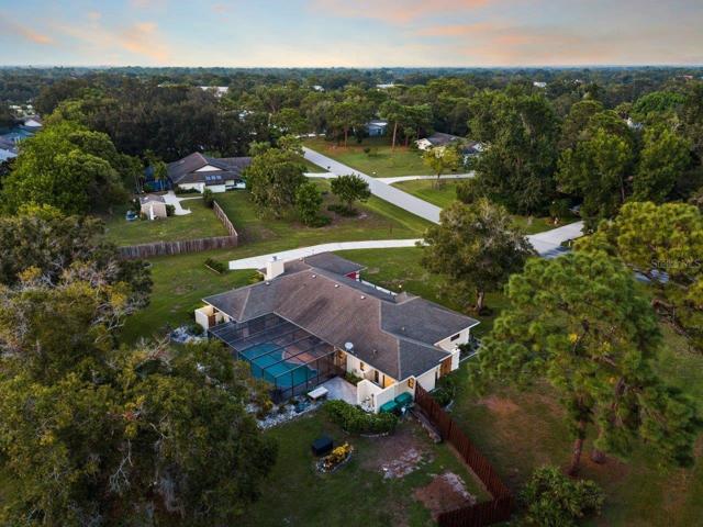 Aerial of the rear elevation of the home showing the newly renovated screened-in lanai, pool, and extended paver patio.