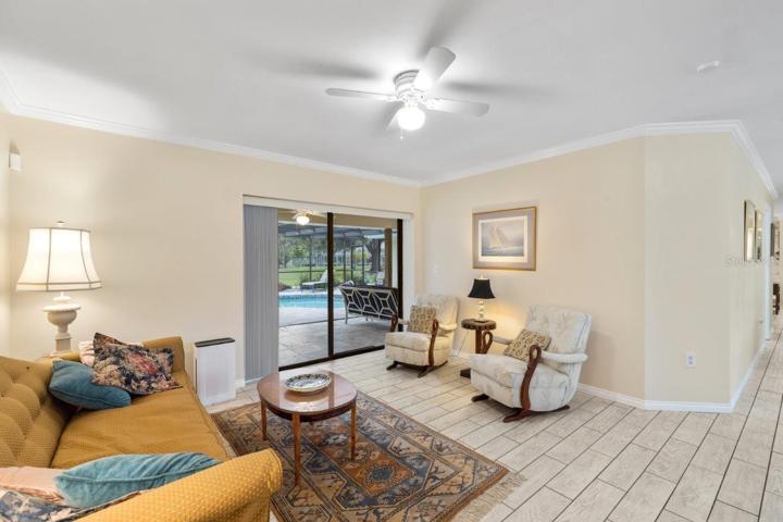 Formal family room located off the front foyer featuring crown molding, porcelain plank tile, and a pocket sliding glass door.
