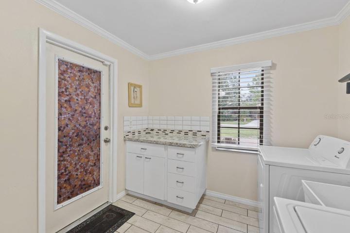Spacious laundry room featuring a laundry sink, and added cabinets with counter space, and  direct access to the garage.