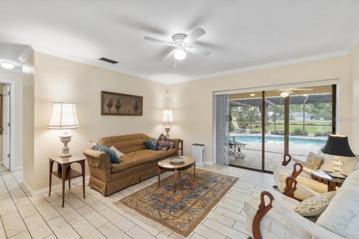 Formal family room located off the front foyer featuring crown molding, porcelain plank tile, and a pocket sliding glass door.