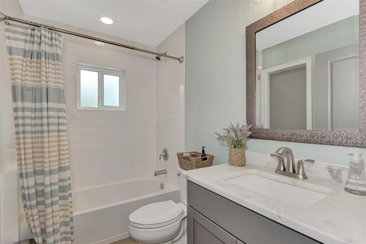 Guest bathroom has granite countertop and a tub/shower combination.