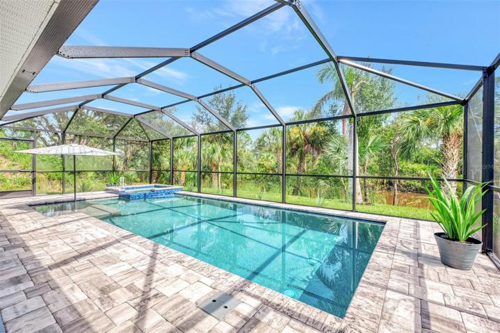 Full view of the brick oaver oatui decj and heated pool and spa.