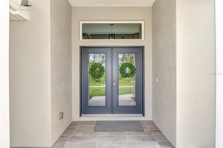 Elegant glass front entry doors with Paver walk-way.