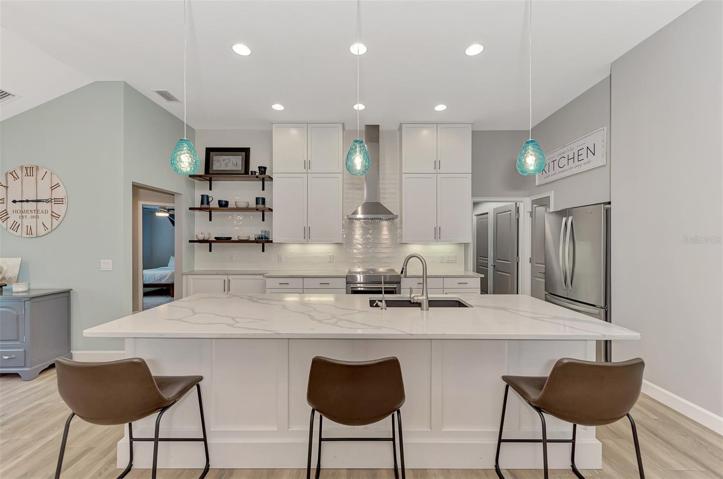 Quartz countertop with stainless steel appliances.  Lovely pendent lighting.