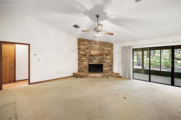 Family room has a stone-stacked fireplace and huge sliders that lead to the serene and private backyard.