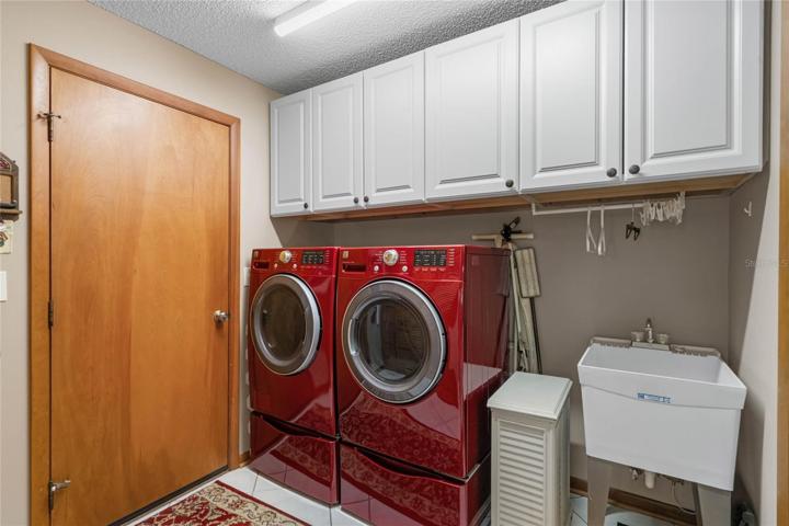 Laundry Room equipped with High-Efficiency Washer & Dryer, additional Cabinetry & Utility Sink