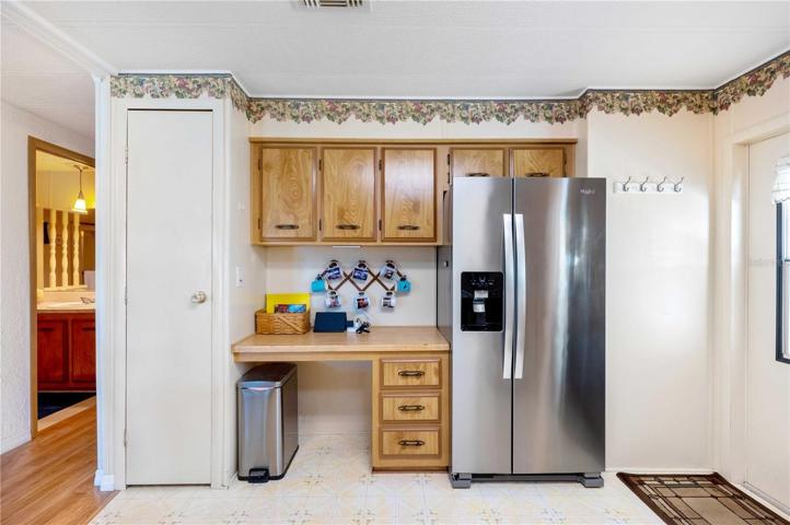 Stainless steel double door refrigerator, closet pantry, and built-in desk.