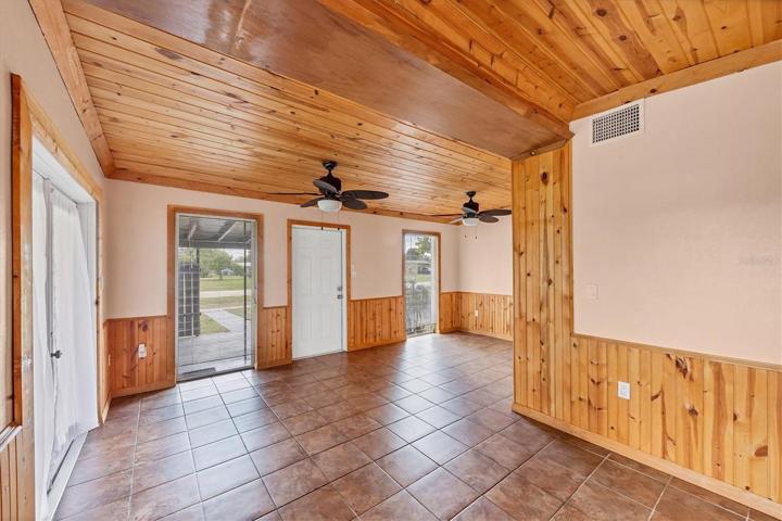 FROM BACK END OF LIVING ROOM TOWARD FRONT ENTRY DOOR AND DINING AREA FAR RIGHT REAR