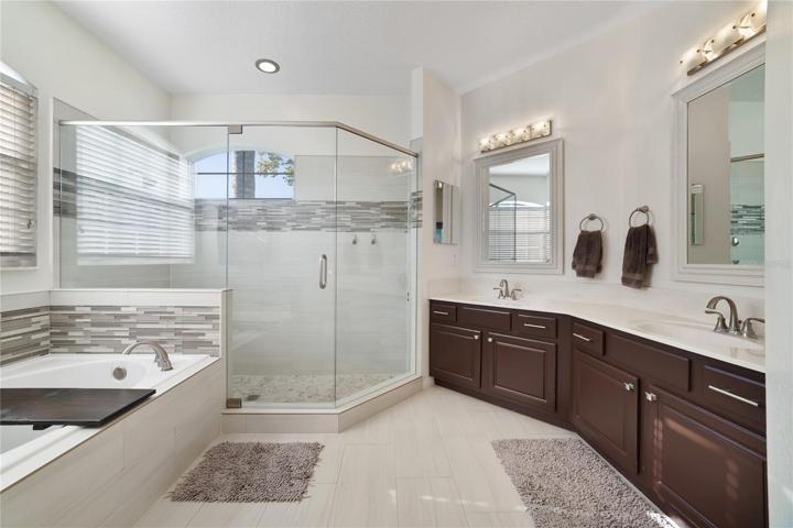 An extended vanity features two sinks and there is an OVERSIZED GLASS ENCLOSED SHOWER and separate SOAKING TUB!