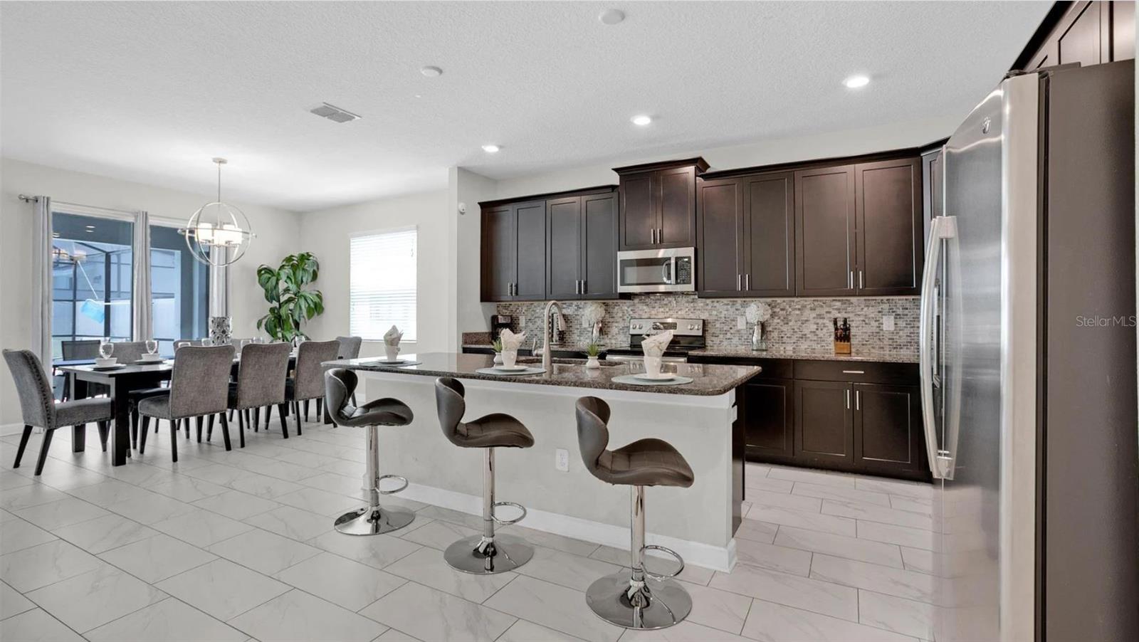 The family chef will love the  dark 42” CABINETS, stainless steel appliances, WALK-IN PANTRY, granite counters, decorative tiled backsplash and a large ISLAND with breakfast bar seating for additional casual dining!