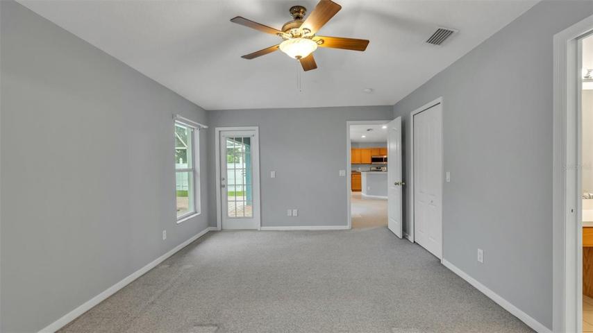 Primary bedroom with door to the patio and view to dinette/kitchen.