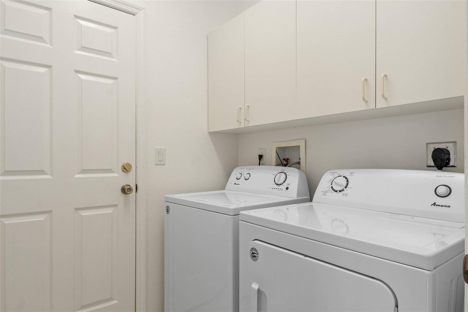 The interior laundry room has additional overhead storage. The door leads into the generous side-load garage.