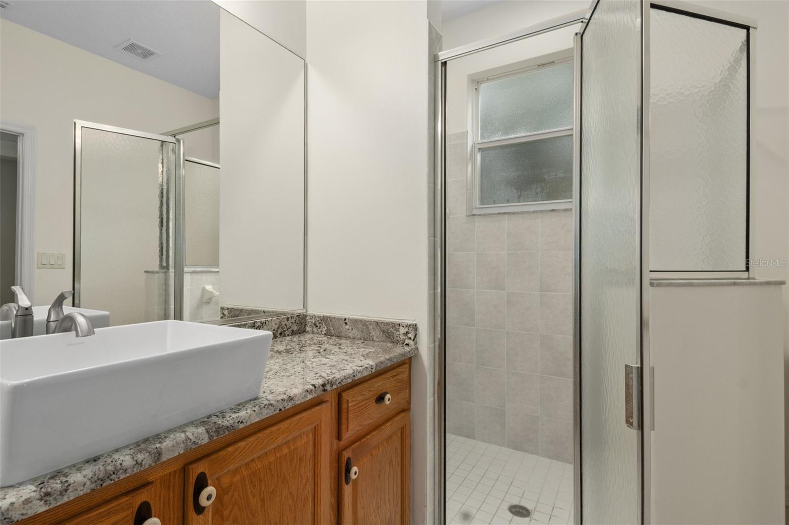The master bath features a generous shower with a window overlooking the pool.