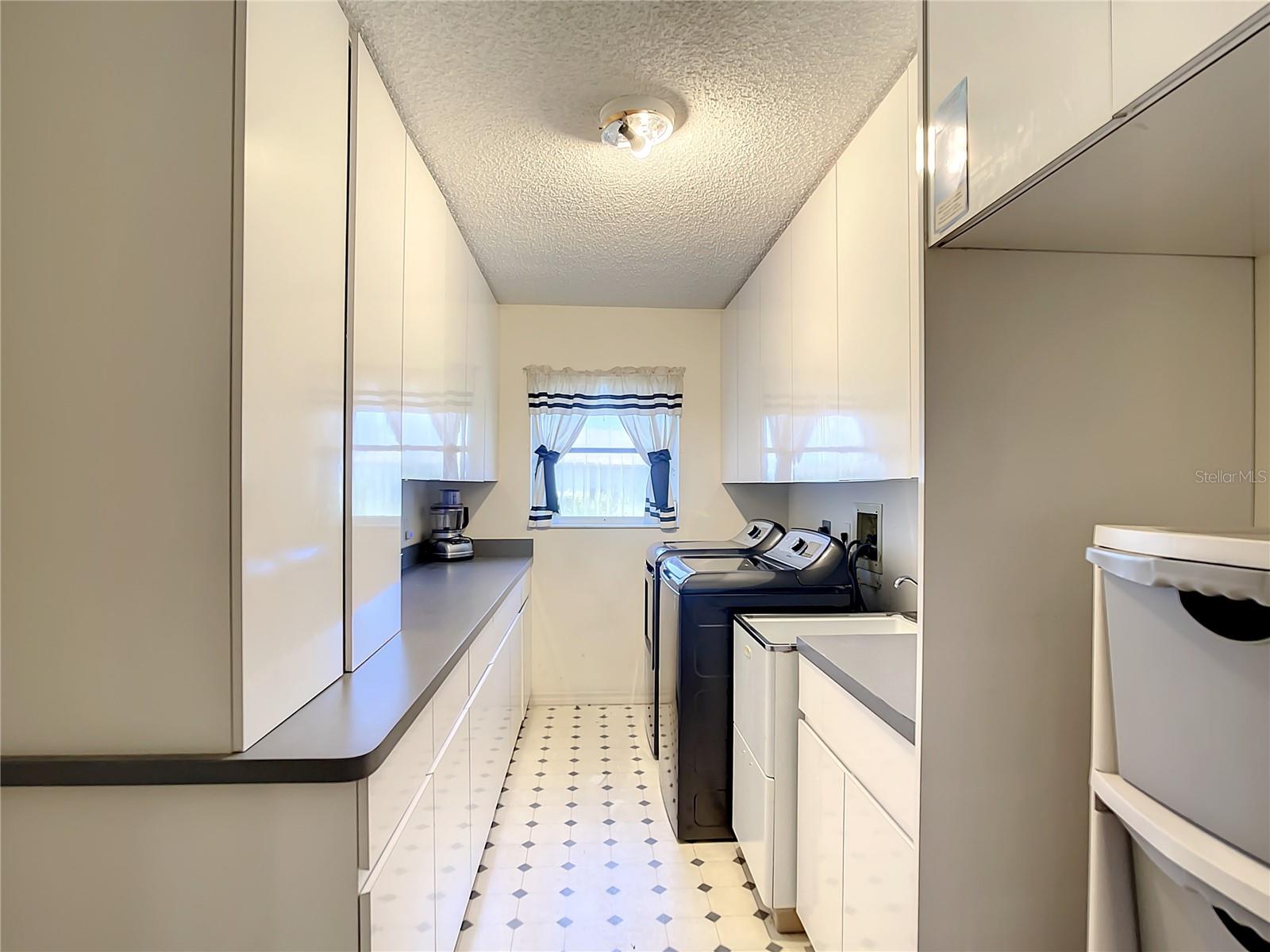Inside laundry room with tons of storage space, cabinets and folding counter.