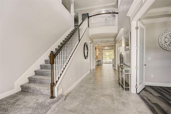 Foyer with soaring 22ft ceiling and double glass door entry foyer with grand staircase to 2nd floor