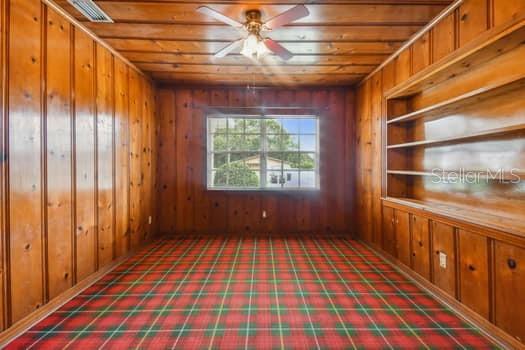 Den/Study with knotty pine walls and ceiling with built in shelves.