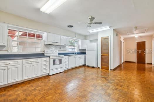 Large kitchen perfect for family gatherings with an abundance of cabinets. The windows overlook the backyard.