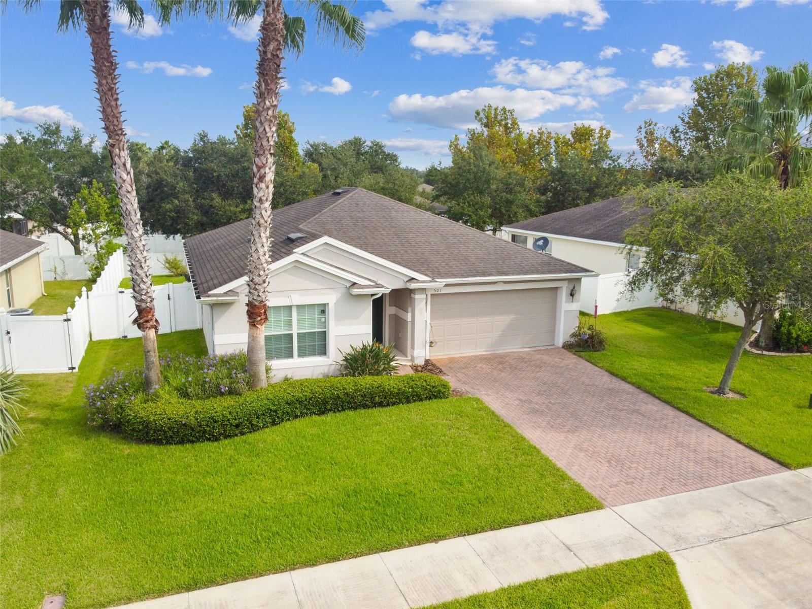 Landscaped yard with stately palm trees,  St. Augustine sod, irrigation system on timer and fully vinyl fenced backyard with gate
