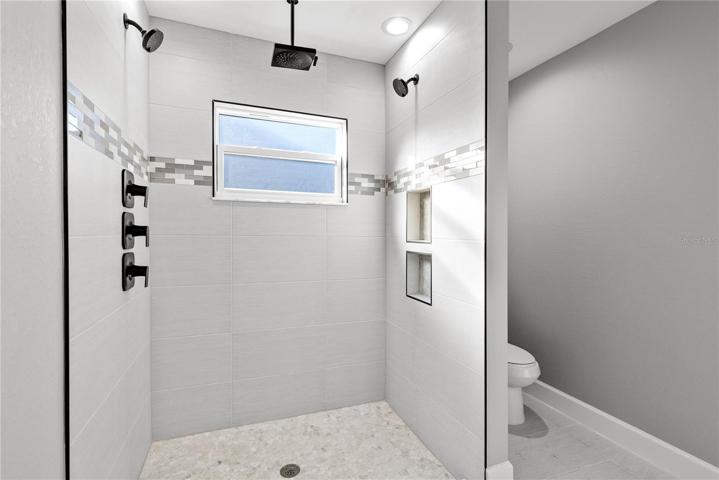 Master bath shower - pride of build shows everywhere!  Multiple shower heads as well as a rain shower provide the ultimate refreshing shower!  Custom tile accents everywhere and two recessed shelves - every detail was thoroughly thoughtthrough and incorporated to make this a forever home!