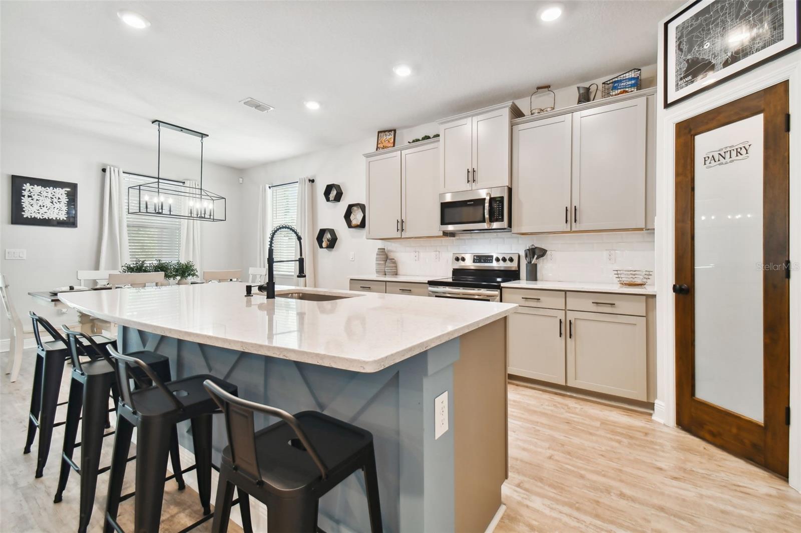 More seating at the kitchen island. Note blue custom woodwork on the face of the island. Stainless appliances. Microwave hood vents directly outside.