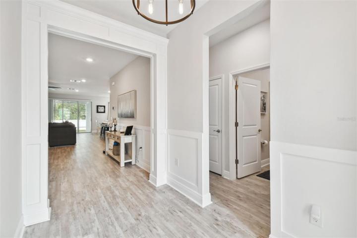 Impressive foyer with decorator wood-design finishes. Custom wainscoting and column framing and depth and beauty. Luxury vinyl throughout the entire home.