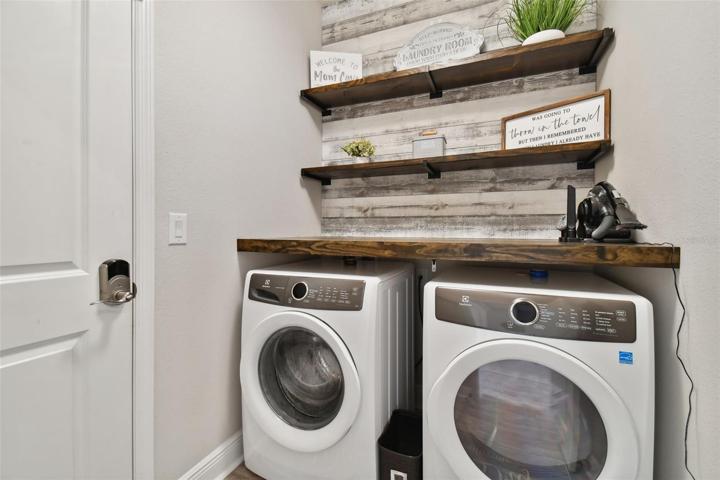 Across the hall, the well appointed laundry room, gives access to the garage. Washer and dryer stay.