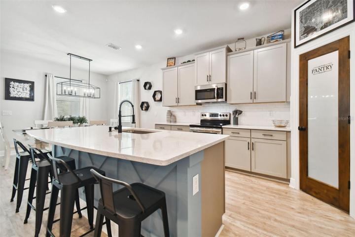 More seating at the kitchen island. Note blue custom woodwork on the face of the island. Stainless appliances. Microwave hood vents directly outside.