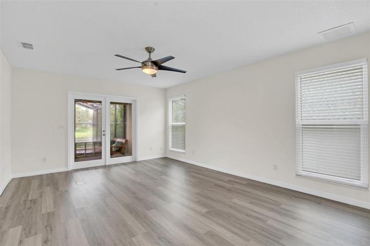 Primary Bedroom with new LVP flooring, fresh paint and French doors to Lanai for access to the pool and spa