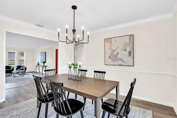 Dining room with crown molding, chair railing, new LVP flooring & new paint.