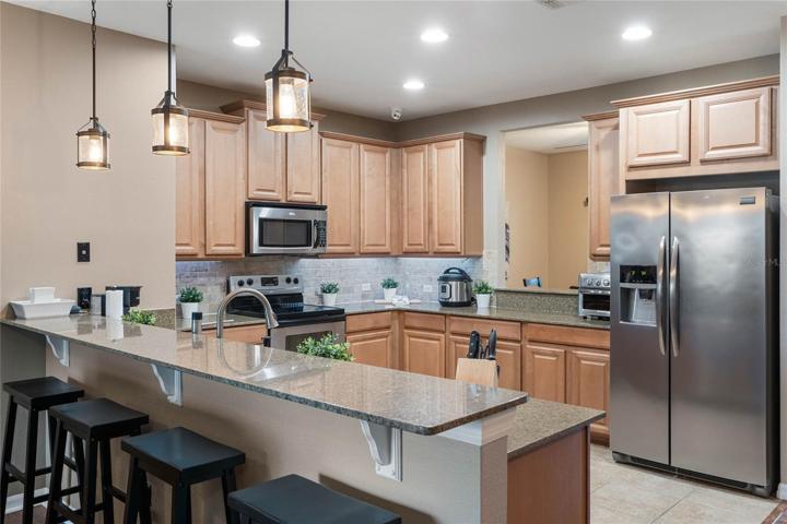 Kitchen w/ updated lighting, appliances, granite countertops, under cabinet lighting & tile backsplash