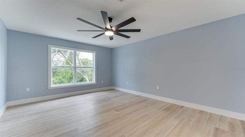 Primary bedroom has large windows for view of green and wooded backyard