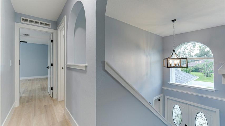 Upstairs hallway showing vaulted ceiling from the foyer and entry to primary bedroom