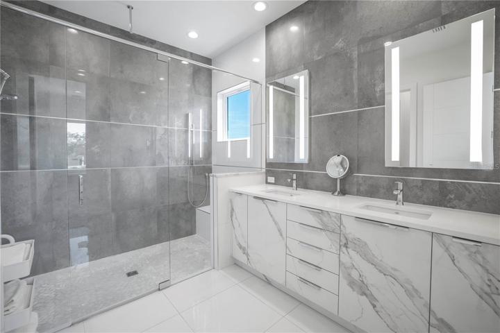 PRIMARY BATHROOM WITH DUAL SINKS AND PORCELAIN TILE FACED CABINETS