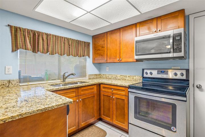 The kitchen features solid granite counter tops and custom wood cabinets with a view to the screened in lanai. Stainless steel appliance package with refrigerator, microwave and oven.