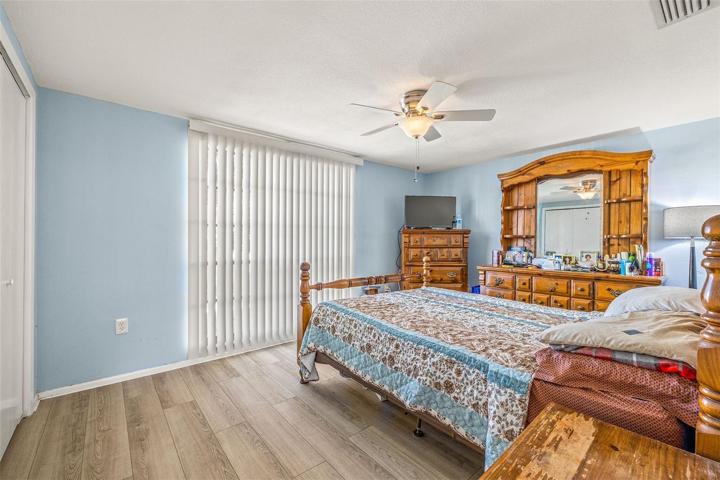 View into main bedroom with ceiling fan, and laminate flooring and double closets.