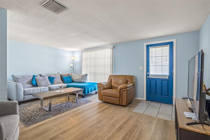 View of Living room toward the front door.  Notice the scraped ceiling and newer laminate flooring.