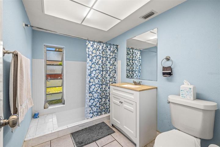 Full main bathroom with updated vanity and large ceramic tiles.
