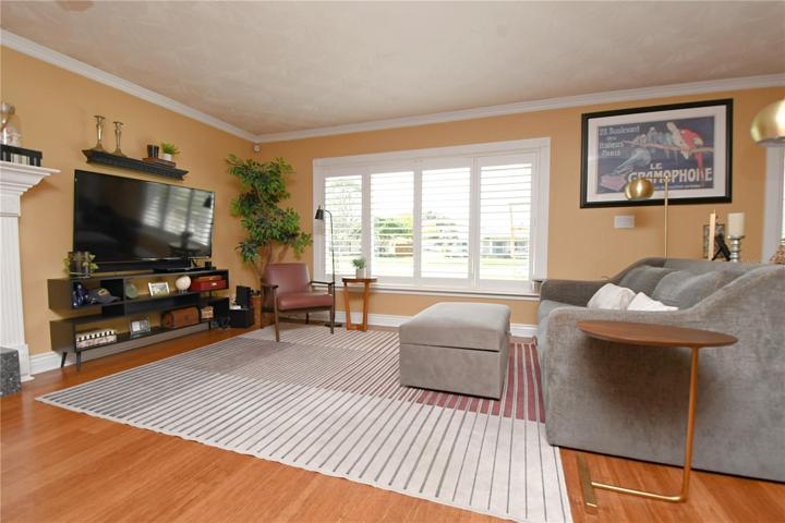 Natural light fills the space through a large window, complemented by vinyl plantation shutters, enhancing the warm and inviting atmosphere.