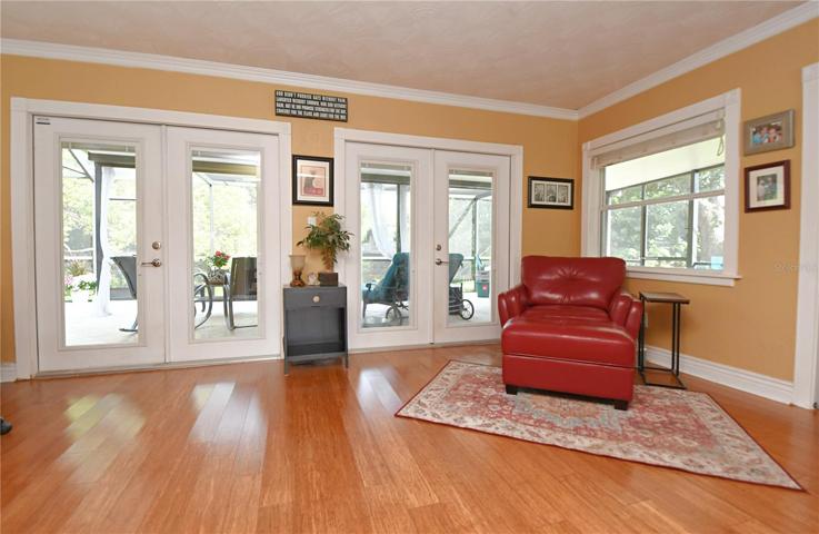 Two large French doors lead to a pool area, complete with a covered porch that offers plenty of seating for entertaining guests or simply relaxing in the shade.