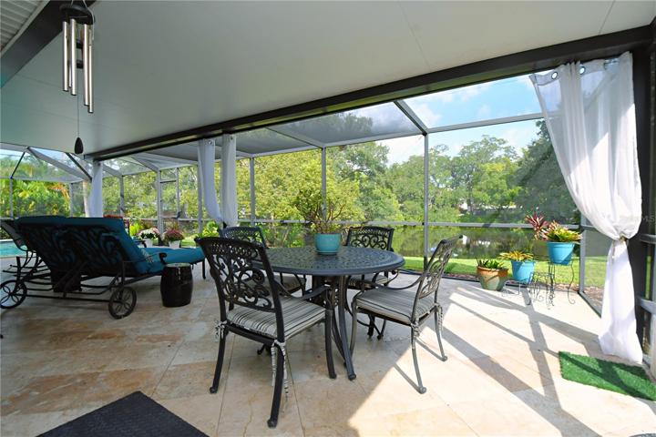 The entire decking area features elegant travertine tile, providing a touch of timeless sophistication.