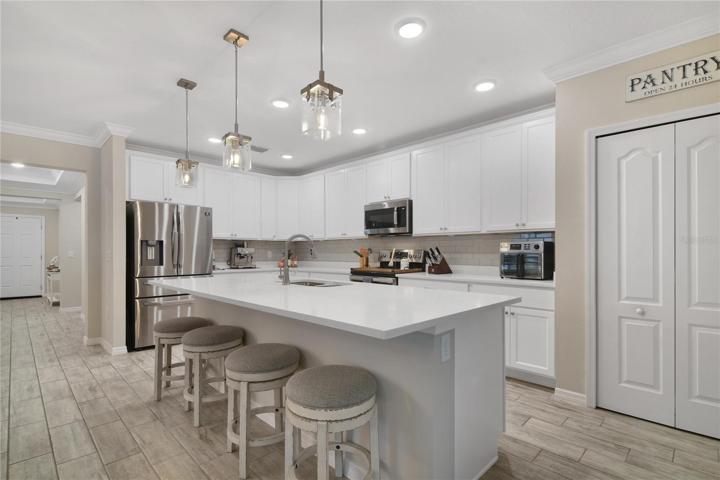 The beautiful kitchen offers the home chef plenty of cabinet and counter space, a subway tile backsplash, stainless steel appliances, a closet pantry for ample storage and a large island under modern pendant lighting with breakfast bar seating; perfect for casual dining or entertaining!