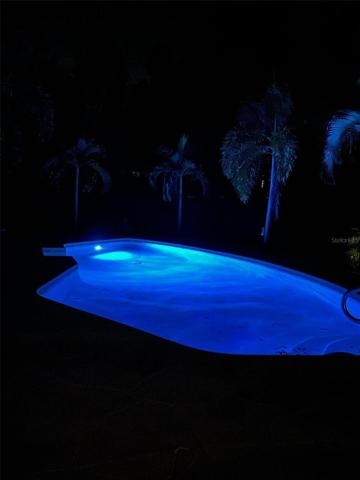 Pool house/studio has a wet bar, refrigerator, electric fireplace, window unit A/C, and concrete flooring.