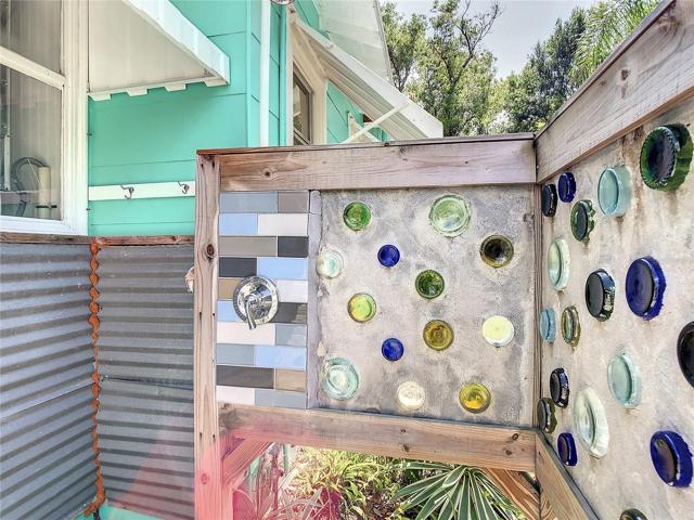Outdoor shower. That's a one-of-a-kind shower enclosure made with cement & the bottoms of glass bottles. The window on the left is where the stackable washer & dry are.