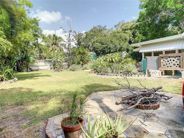 View from west side of yard, looking northeast. The square glass & cement is the custom made outdoor shower enclosure. The borders for the landscaping are the same materials; cement with glass bottle bottoms.